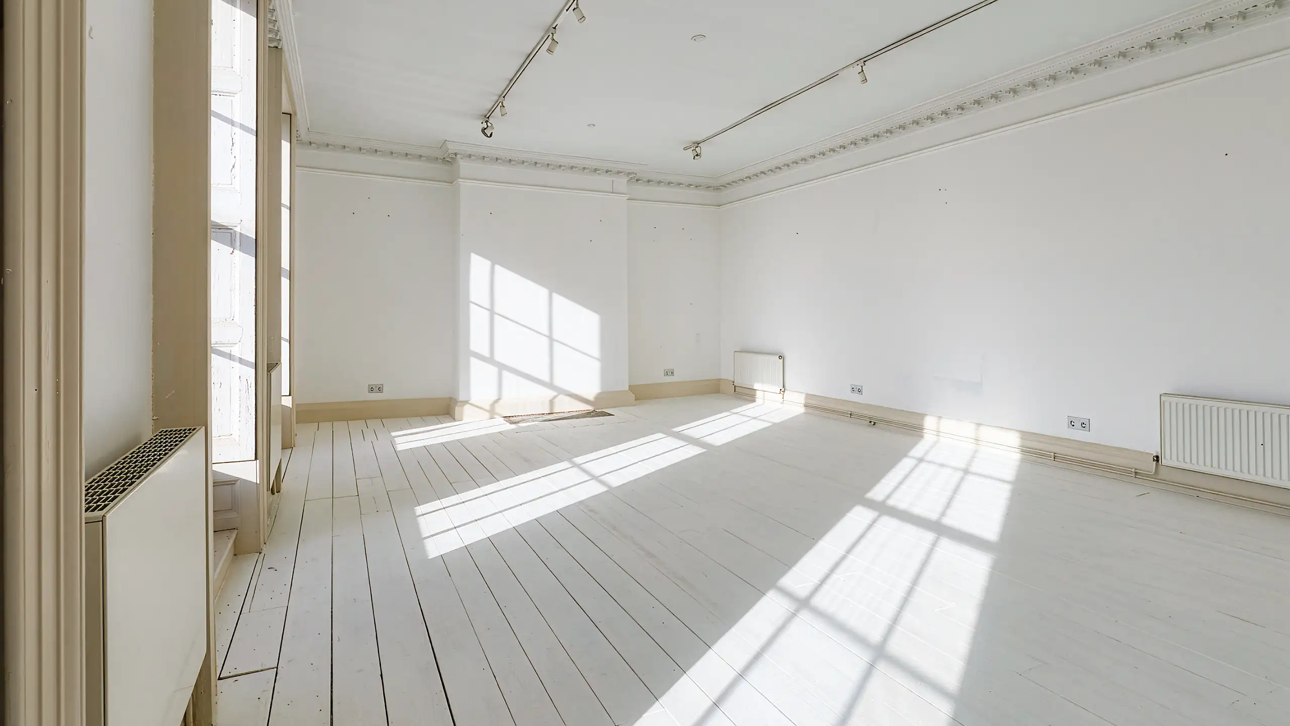 Interior view of the large front studio at South Quay Gallery, featuring tall sash windows and white walls in a historic setting.