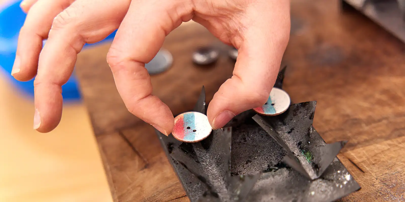 Close-up of hands working on a colorful handcrafted enamel button during a workshop at South Quay Gallery in Great Yarmouth.
