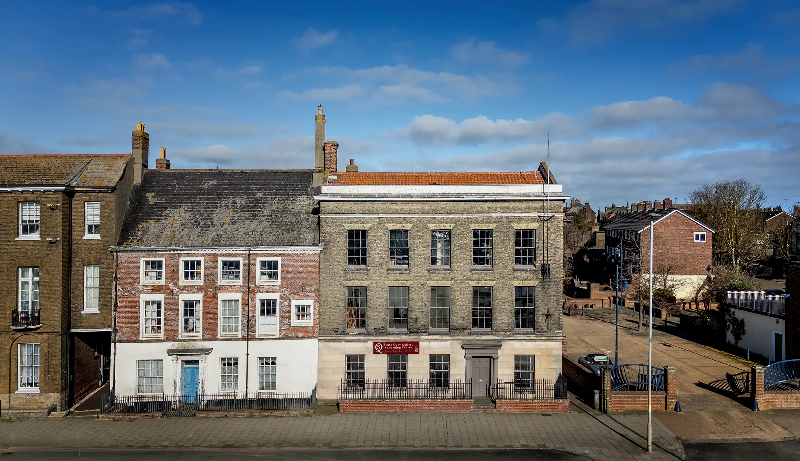 Exterior view of South Quay Gallery, a three-story historic brick building with large windows and a stone ground floor in Great Yarmouth, Norfolk.